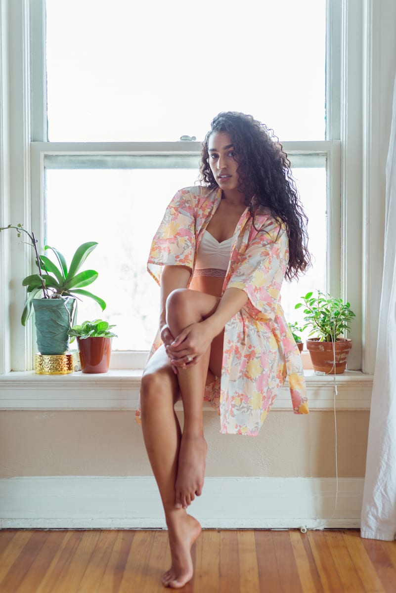 boudoir | Boudoir Photography | model | From the Hip Photo | Model in transparent robe sits on a window sill holding one knee close