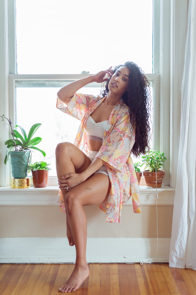 boudoir | Boudoir Photography | model | From the Hip Photo | Model in transparent peach colored robe sits on window sill and touches hair