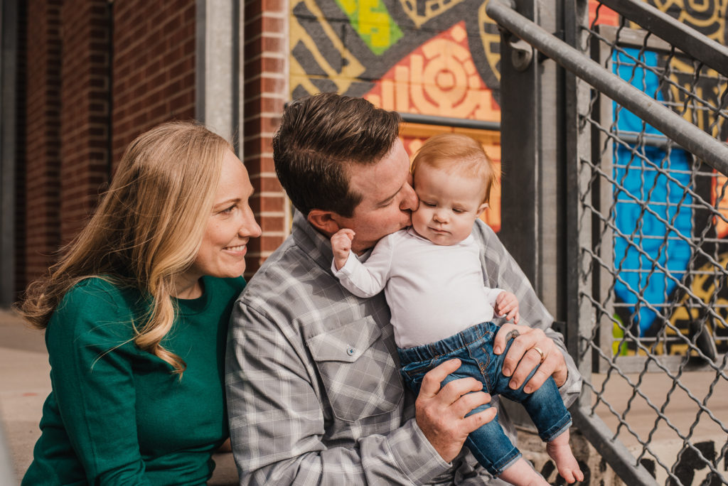 RiNo Art District smiling parents kissing baby happy family photo urban colorful 