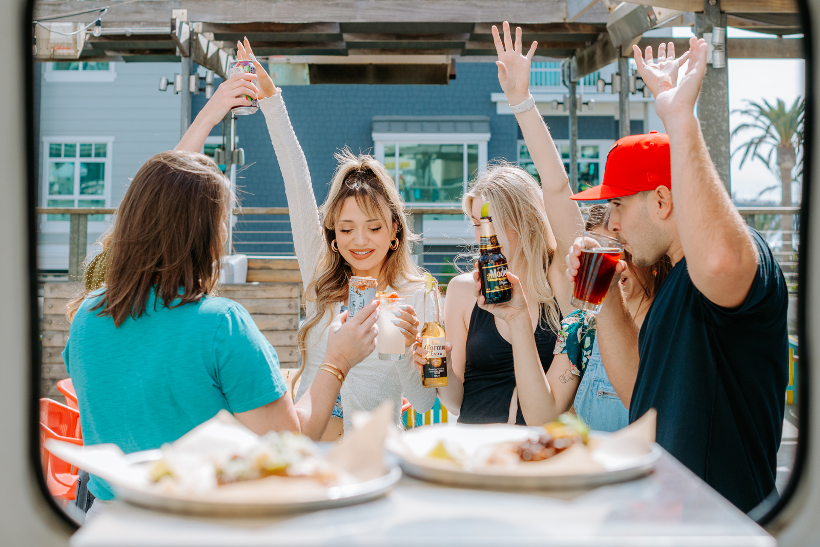 A group of young adults hold their hands up as they toast after a meal | Bethesda, MD | Oceanside, CA