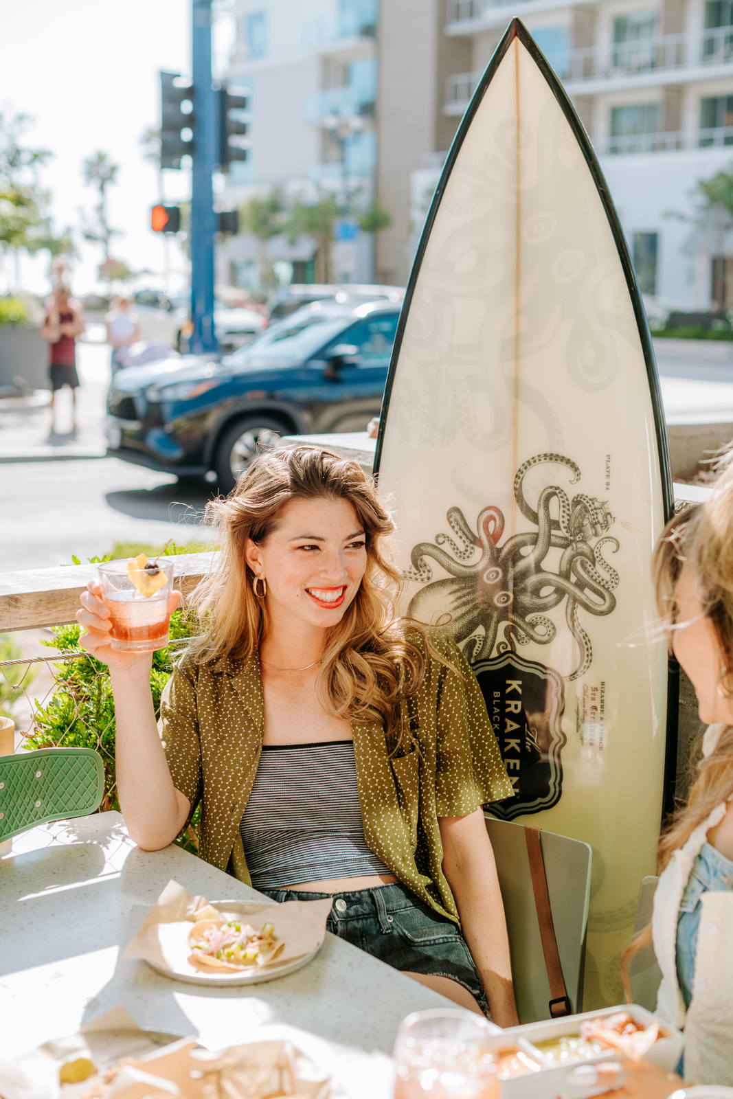 West to East Coast with Hello Betty | Two women drinking on patio by surfboard with kraken print on it | Bethesda, MD | Oceanside, CA