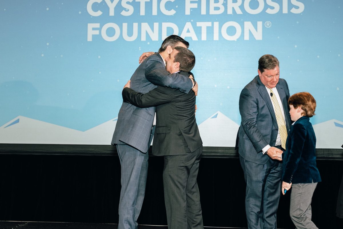Emotional embrace on stage at Cystic Fibrosis Foundation nonprofit conference event