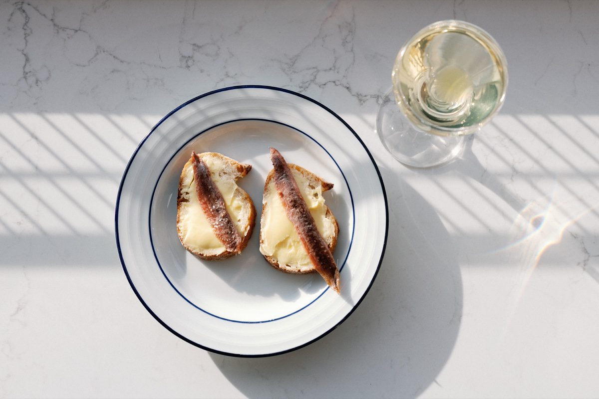 Anchovy toasts with white wine on marble