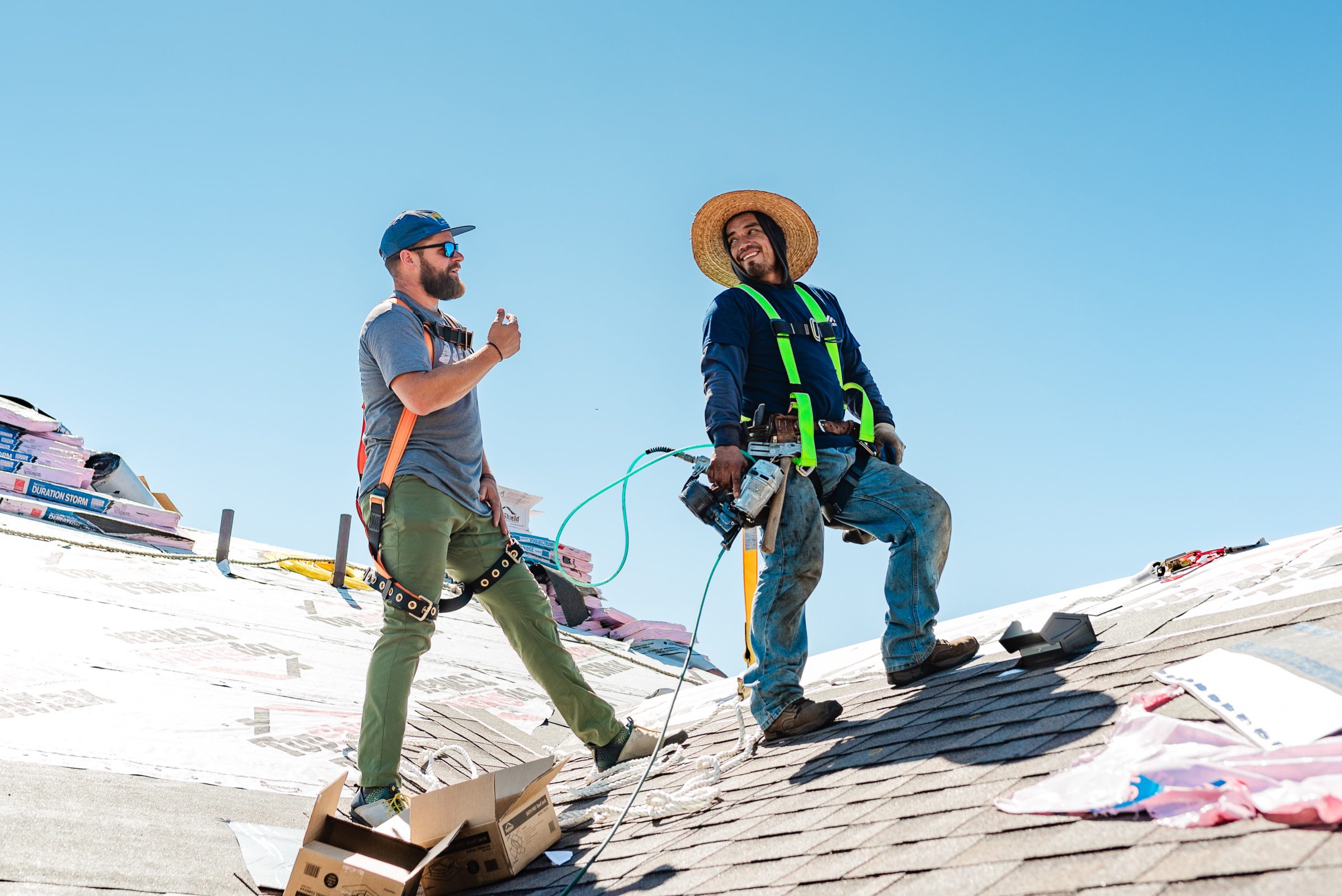 Crew action on the roof -- safety harnesses, job-site moment