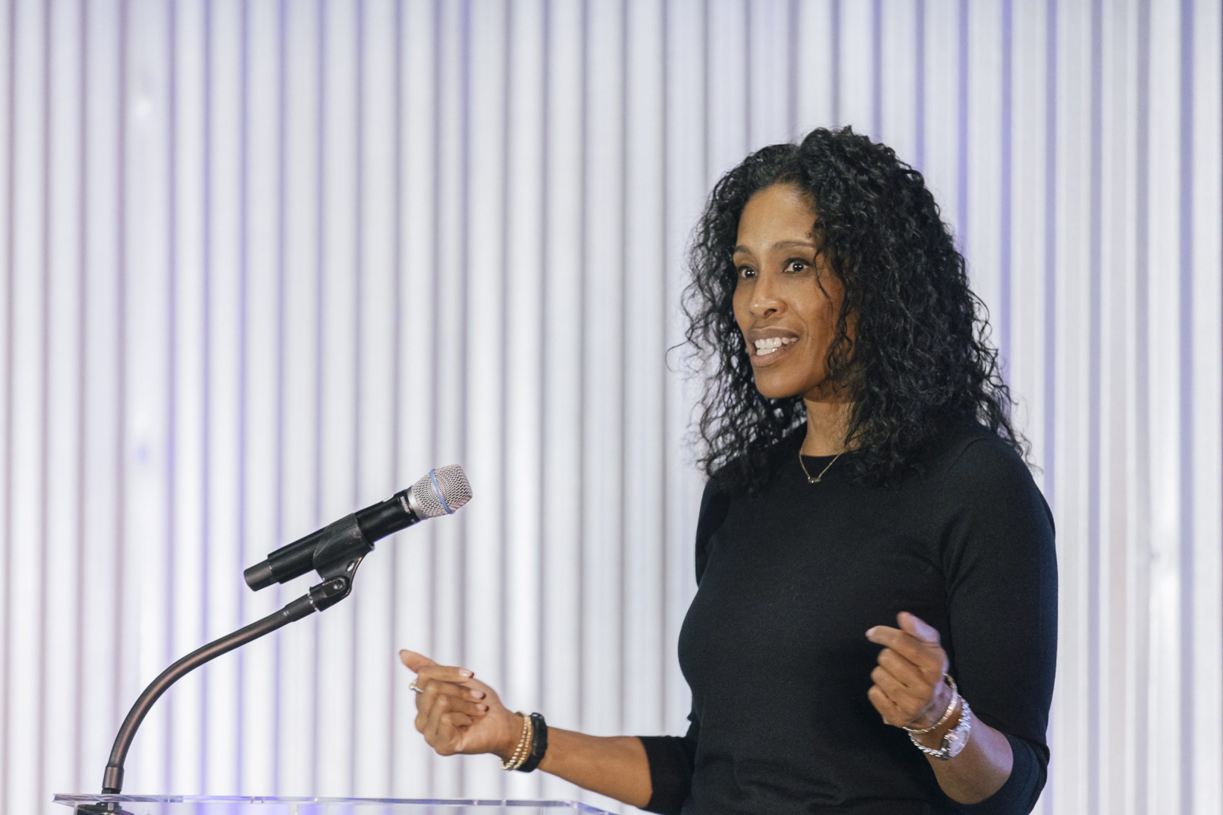 On-stage award presentation -- speaker at the podium, sharp light + warm crowd