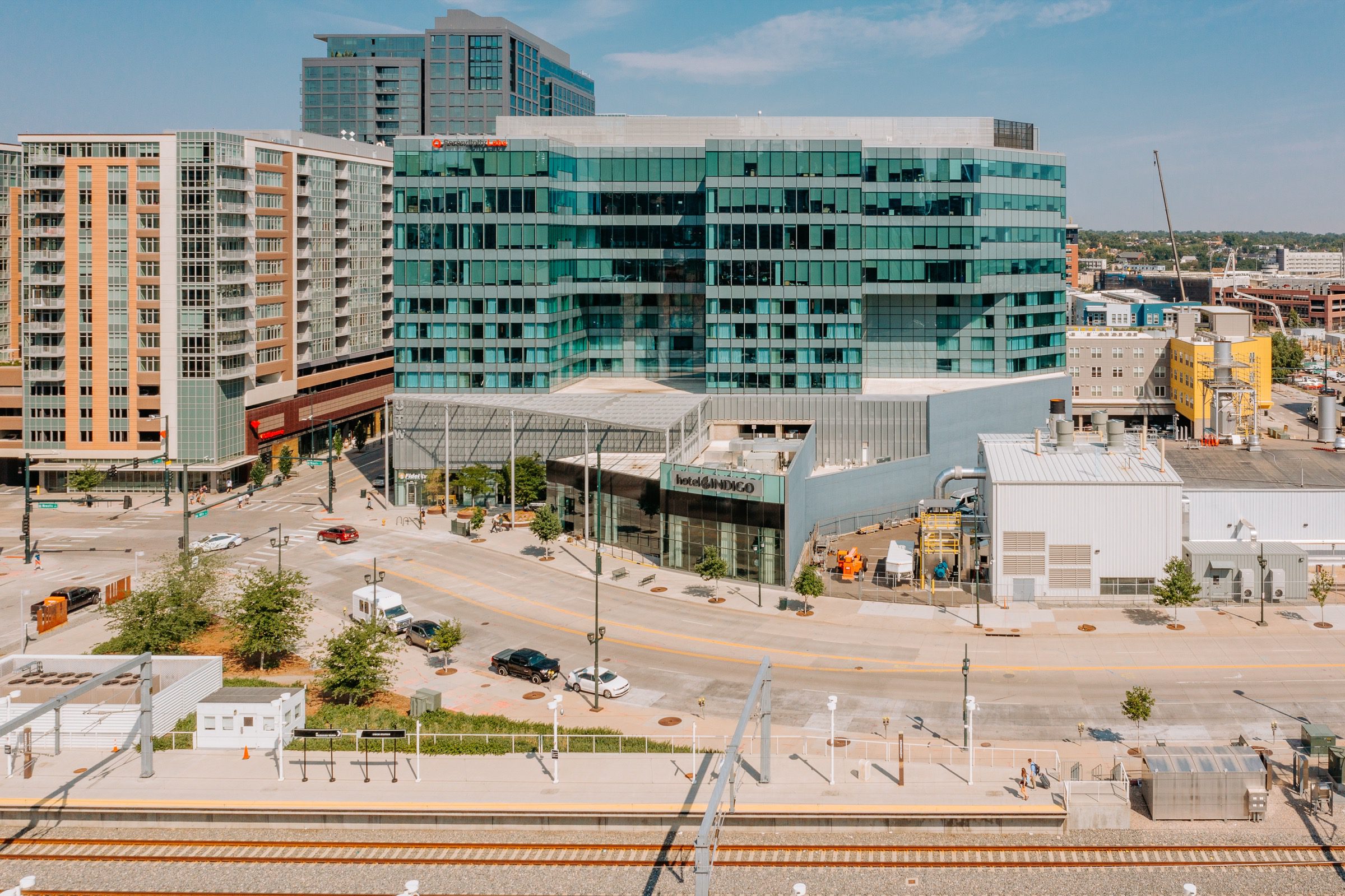 Drone view of modern glass commercial building at street level with light rail