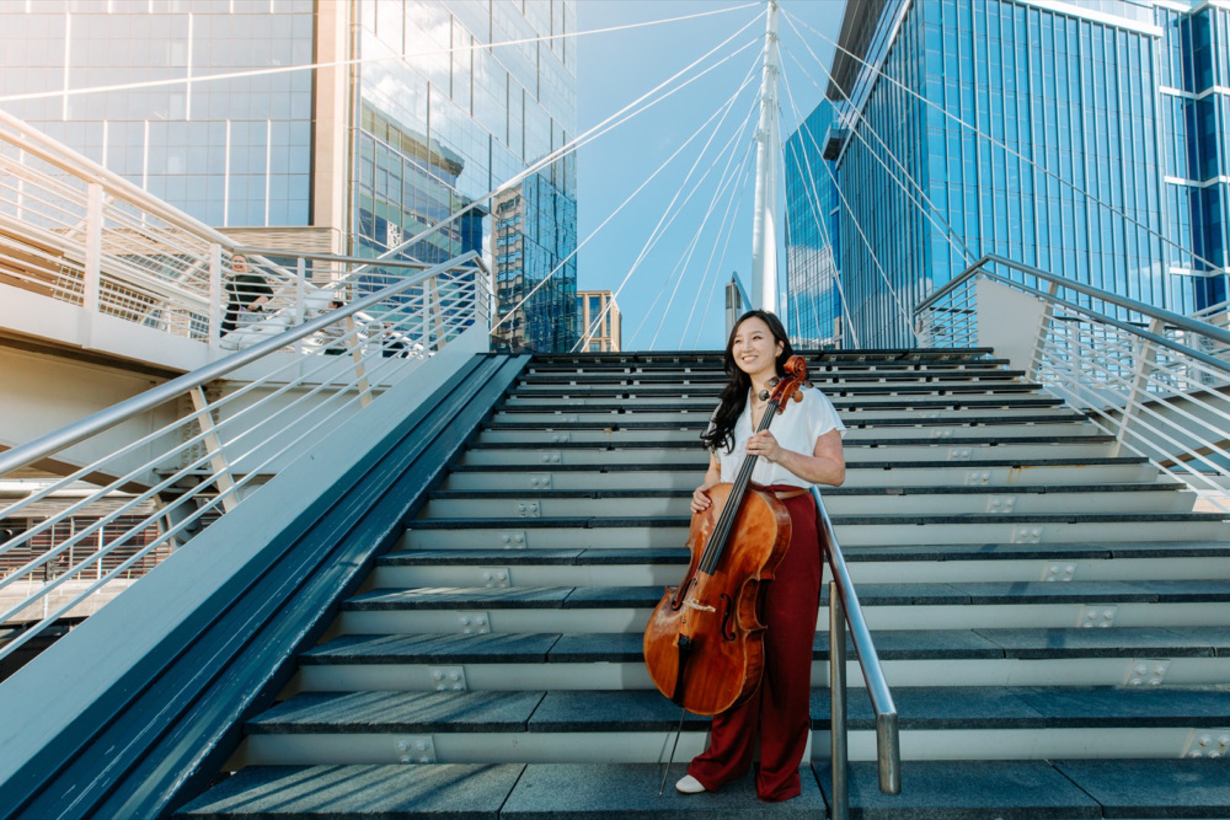 Cellist beneath the Millennium Bridge spire -- downtown stairs + glass towers
