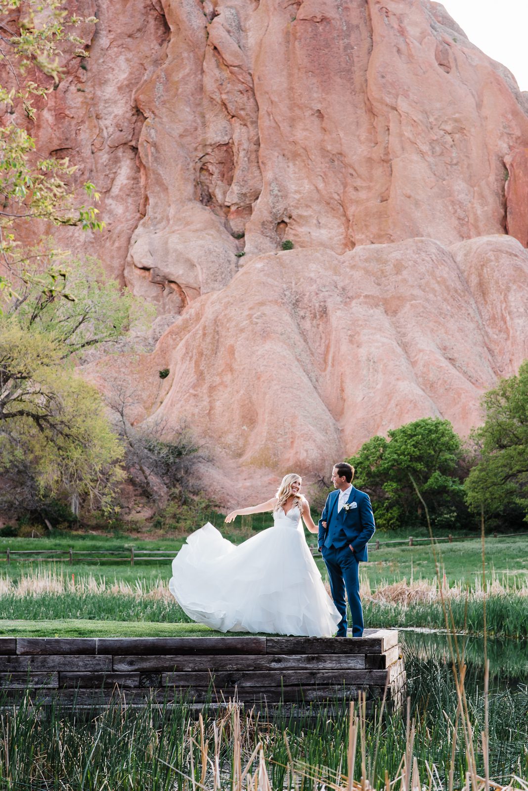 Bride and groom walking below the red sandstone fins at Arrowhead Golf Club