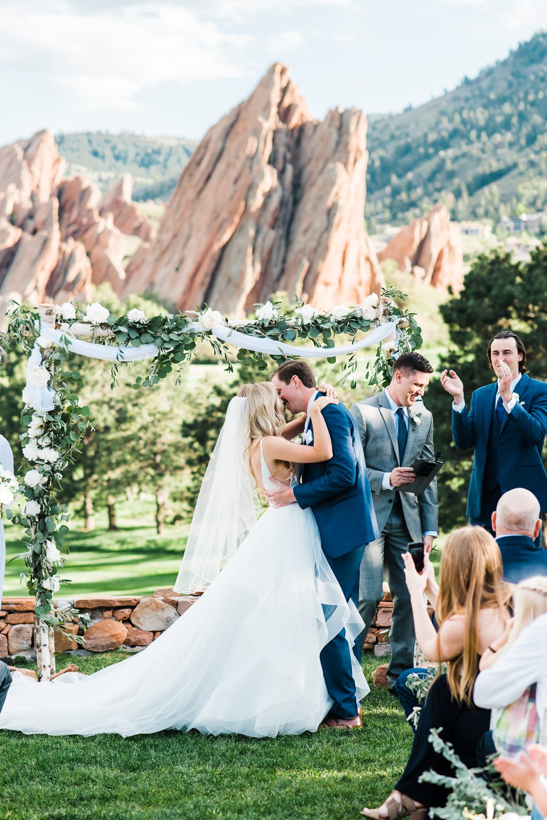 First kiss beneath a floral arch on the fairway at Arrowhead Golf Club