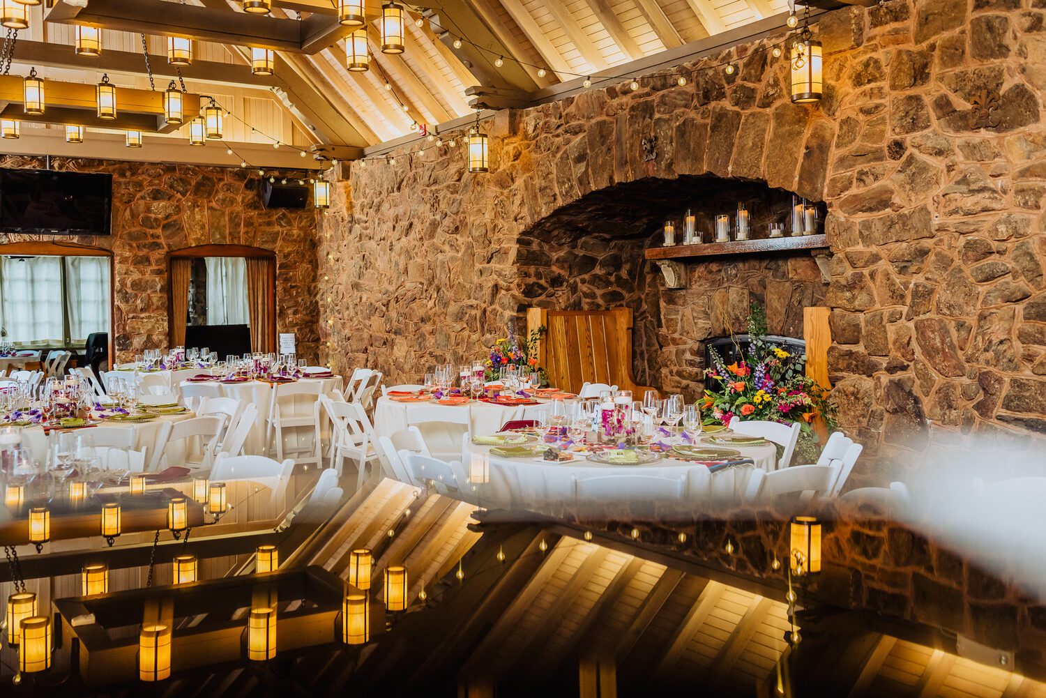The Fireside Room at Boettcher Mansion set for a wedding dinner, stone walls and warm lantern light