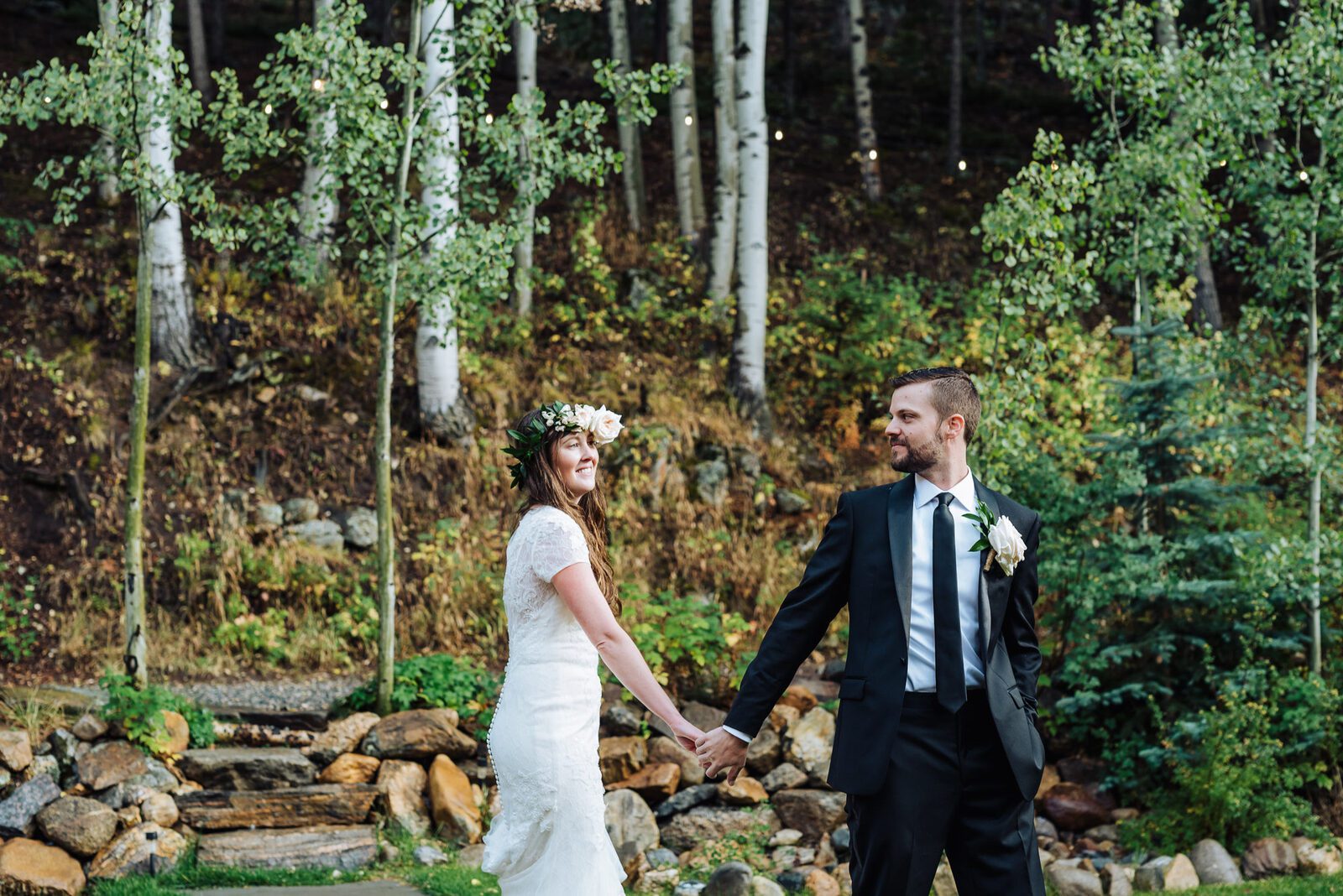 Newlyweds walking hand in hand below the aspen slope at Blackstone Rivers Ranch