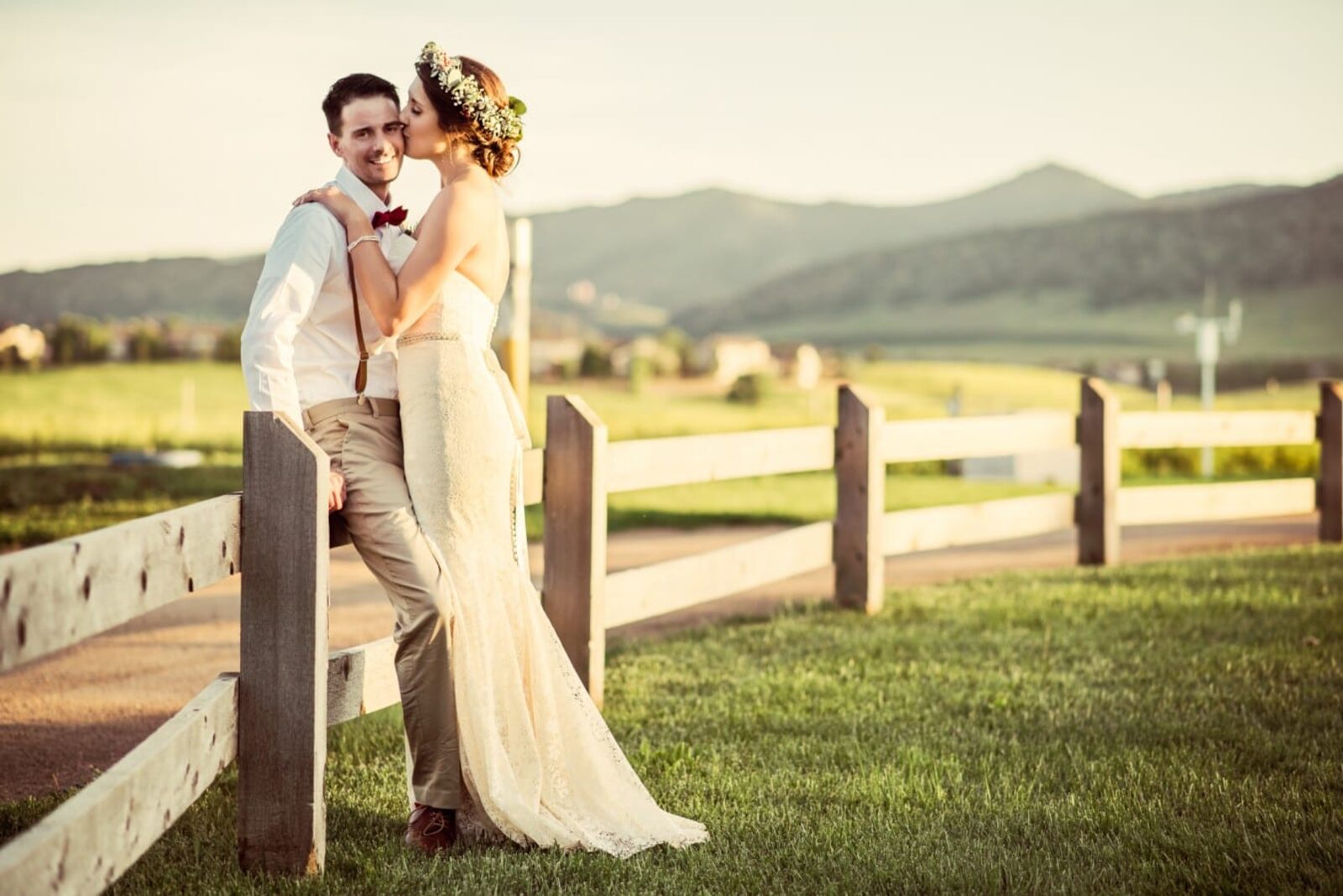 Bride and groom beside a split-rail fence with the Front Range foothills behind them at Denver Botanic Gardens Chatfield Farms