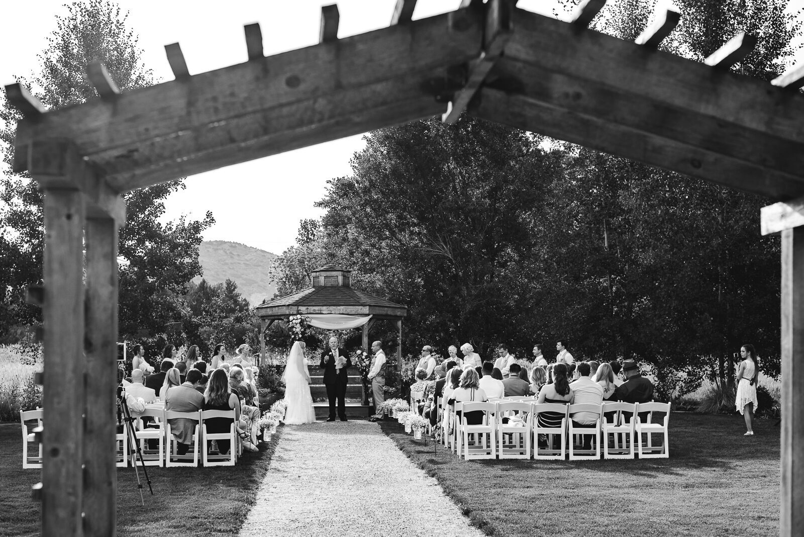 Wedding ceremony under the Open Air Chapel pergola with the foothills beyond at Chatfield Farms