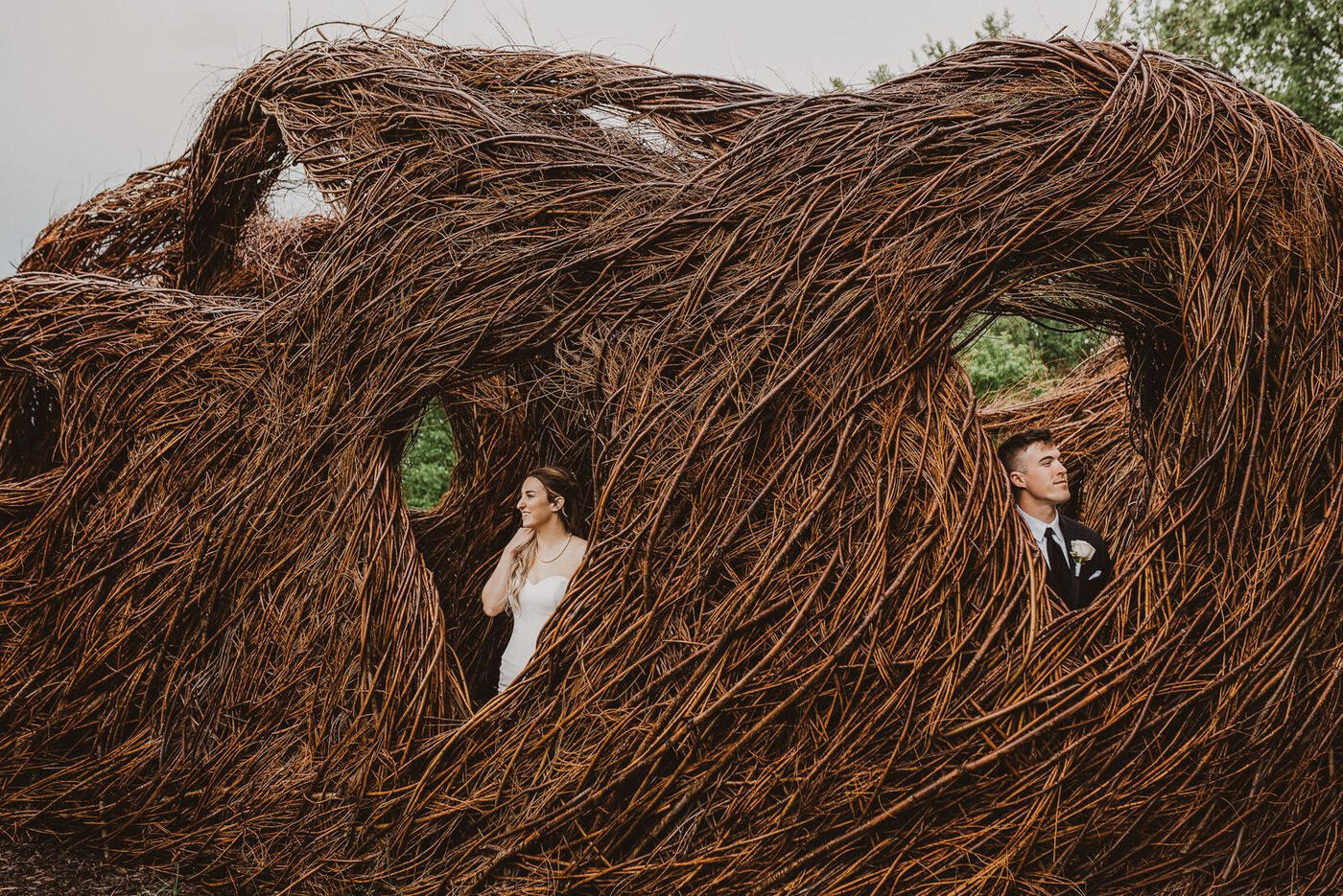 Bride and groom framed inside the woven willow sculpture at Chatfield Farms