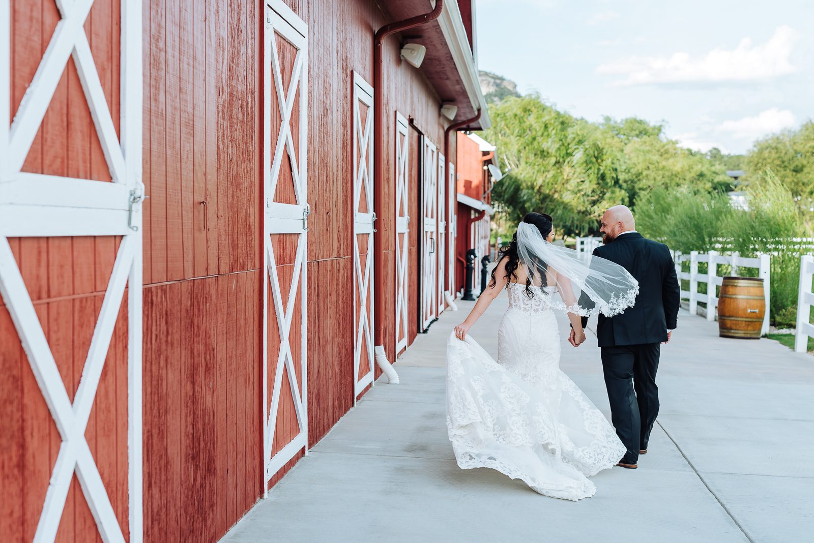 Bride and groom walking past the red barn doors at Crooked Willow Farms