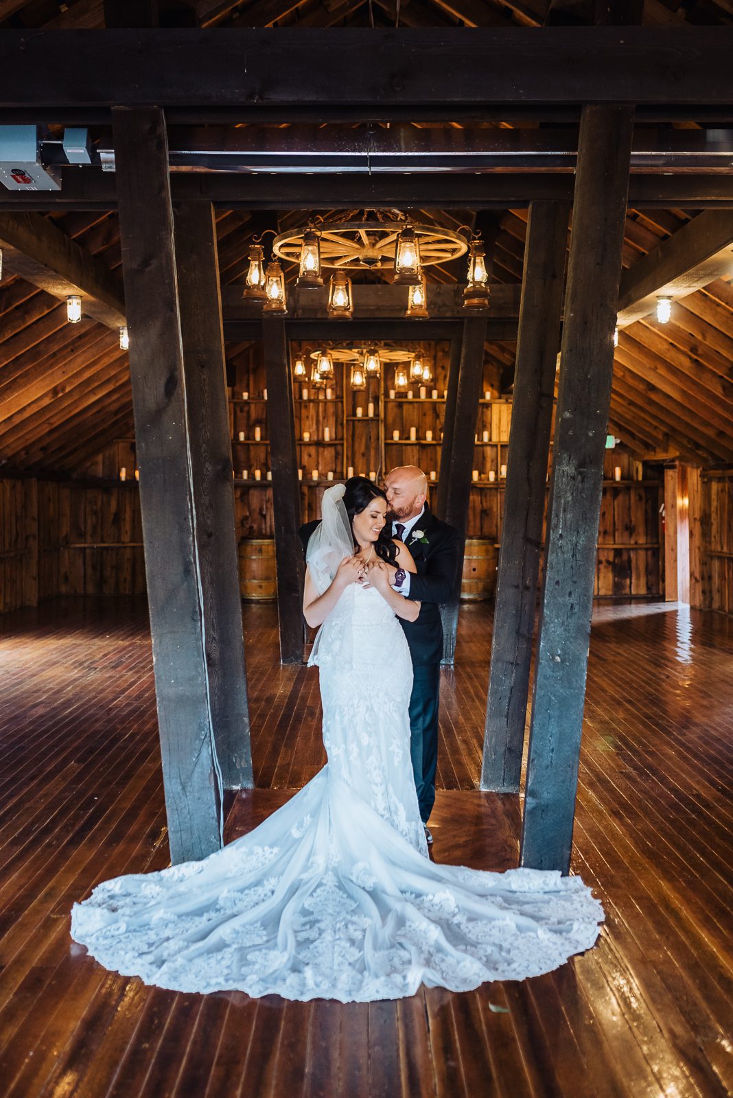 Bride and groom inside the timber barn at Crooked Willow Farms, chandeliers overhead