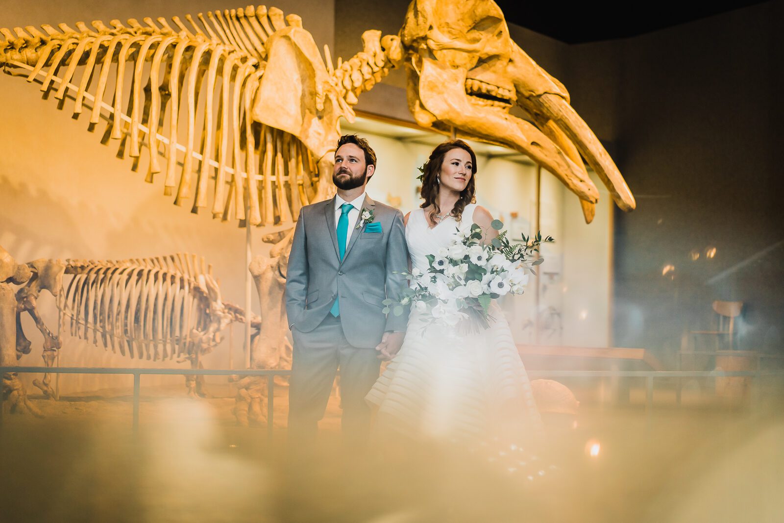 Bride and groom beneath a dinosaur skeleton at a Denver Museum of Nature and Science wedding