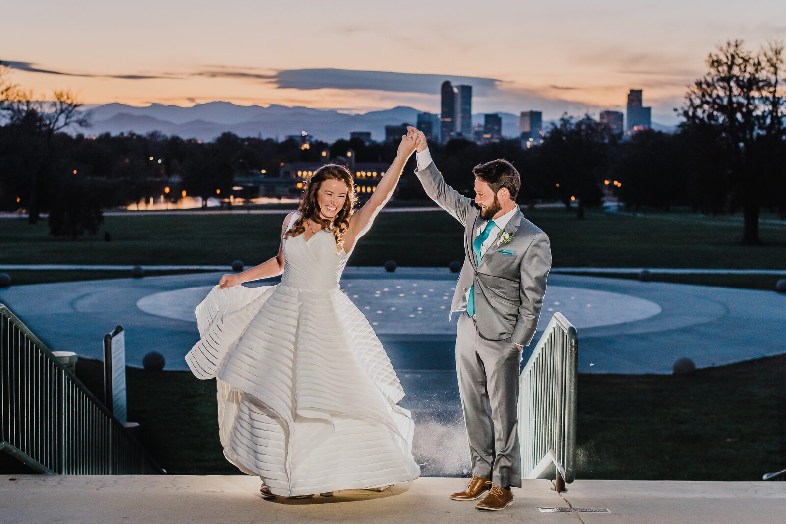 Bride and groom dancing on the Anschutz Family Sky Terrace with the Denver skyline behind them