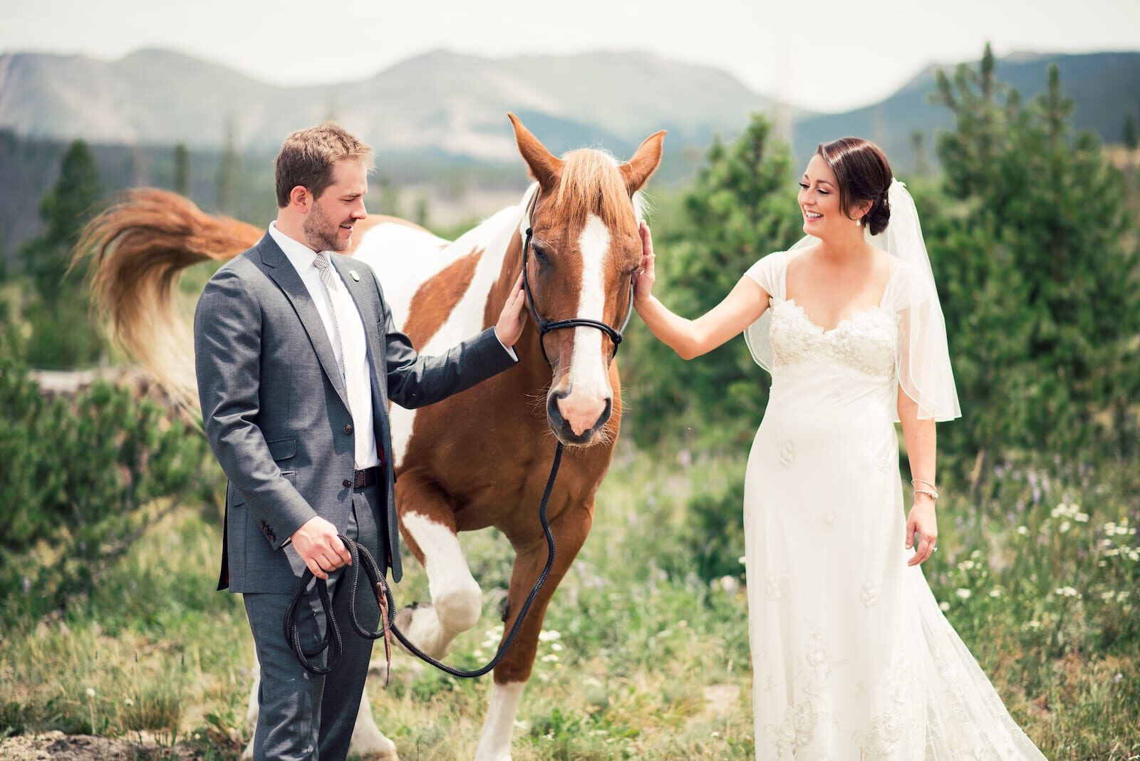 Bride and groom with a ranch horse and the Continental Divide behind them at Devil's Thumb Ranch