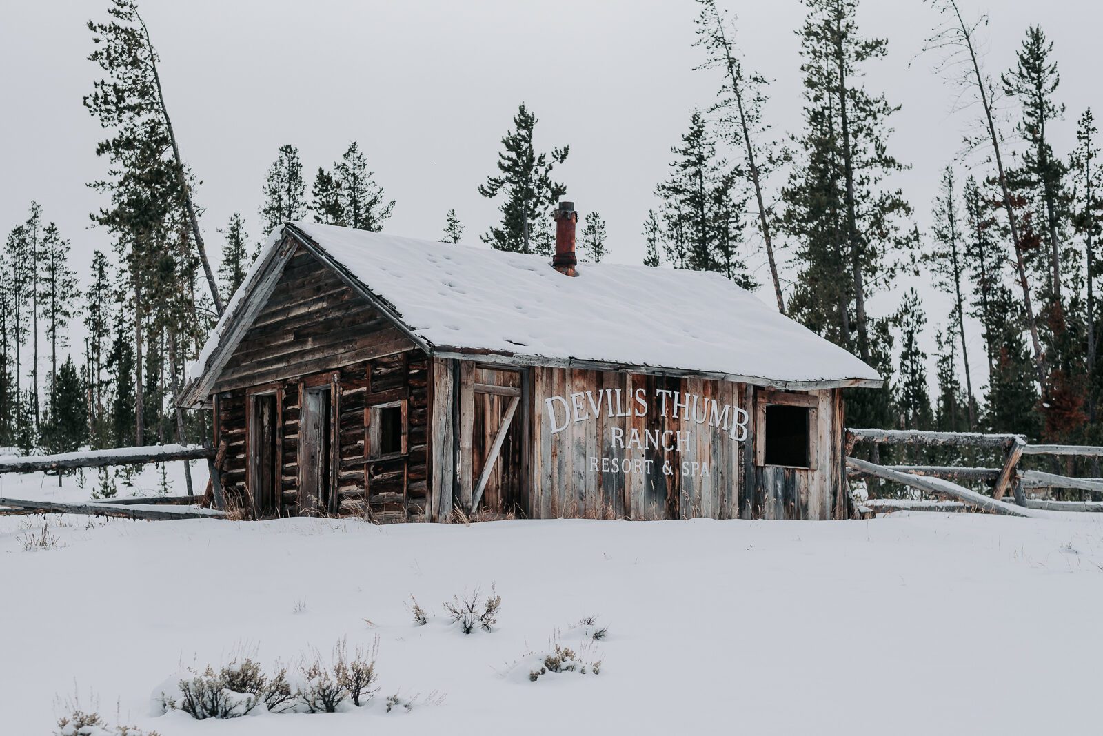 A historic log cabin in the snow on the Devil's Thumb Ranch property