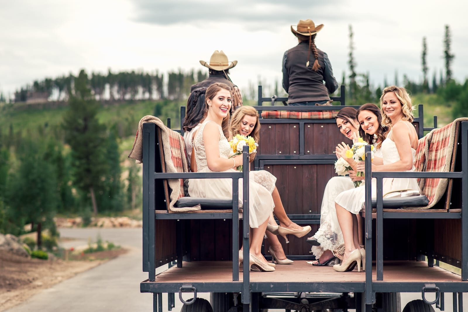 Bridesmaids riding the horse-drawn wagon at a Devil's Thumb Ranch wedding