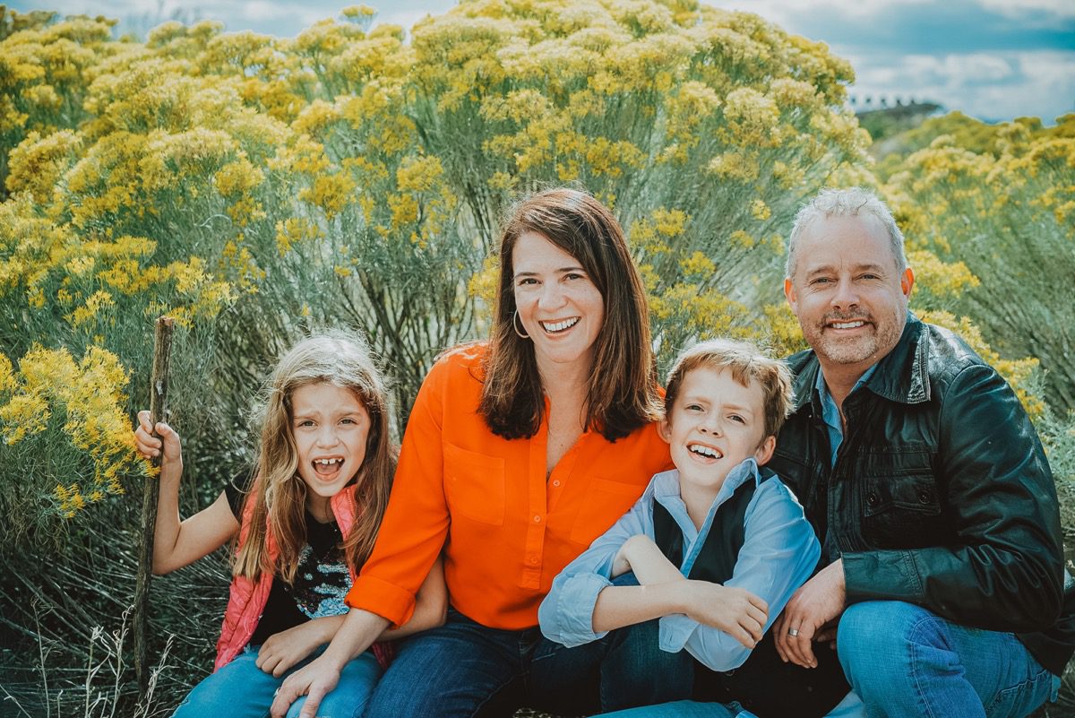 Family of four laughing together among blooming rabbitbrush at Bluff Lake Nature Center, Denver