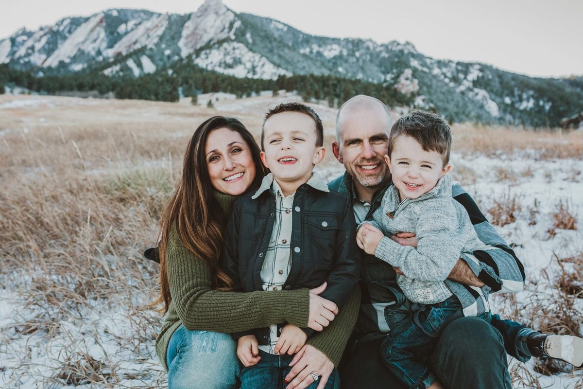 Family portrait with the Flatirons behind them at Chautauqua Park in Boulder