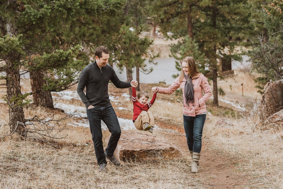 Parents swinging their child between them at Mount Falcon Park in the Colorado foothills
