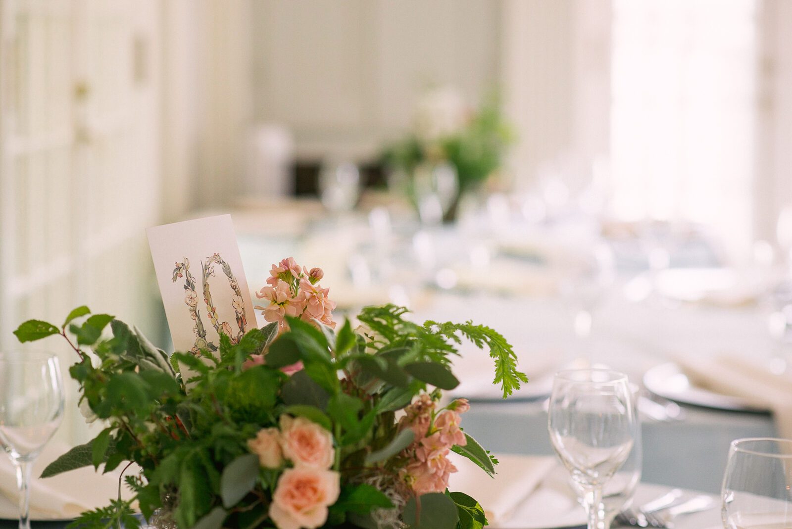 Reception table with a low peach and greenery centrepiece in a light-filled room at the Grant-Humphreys Mansion