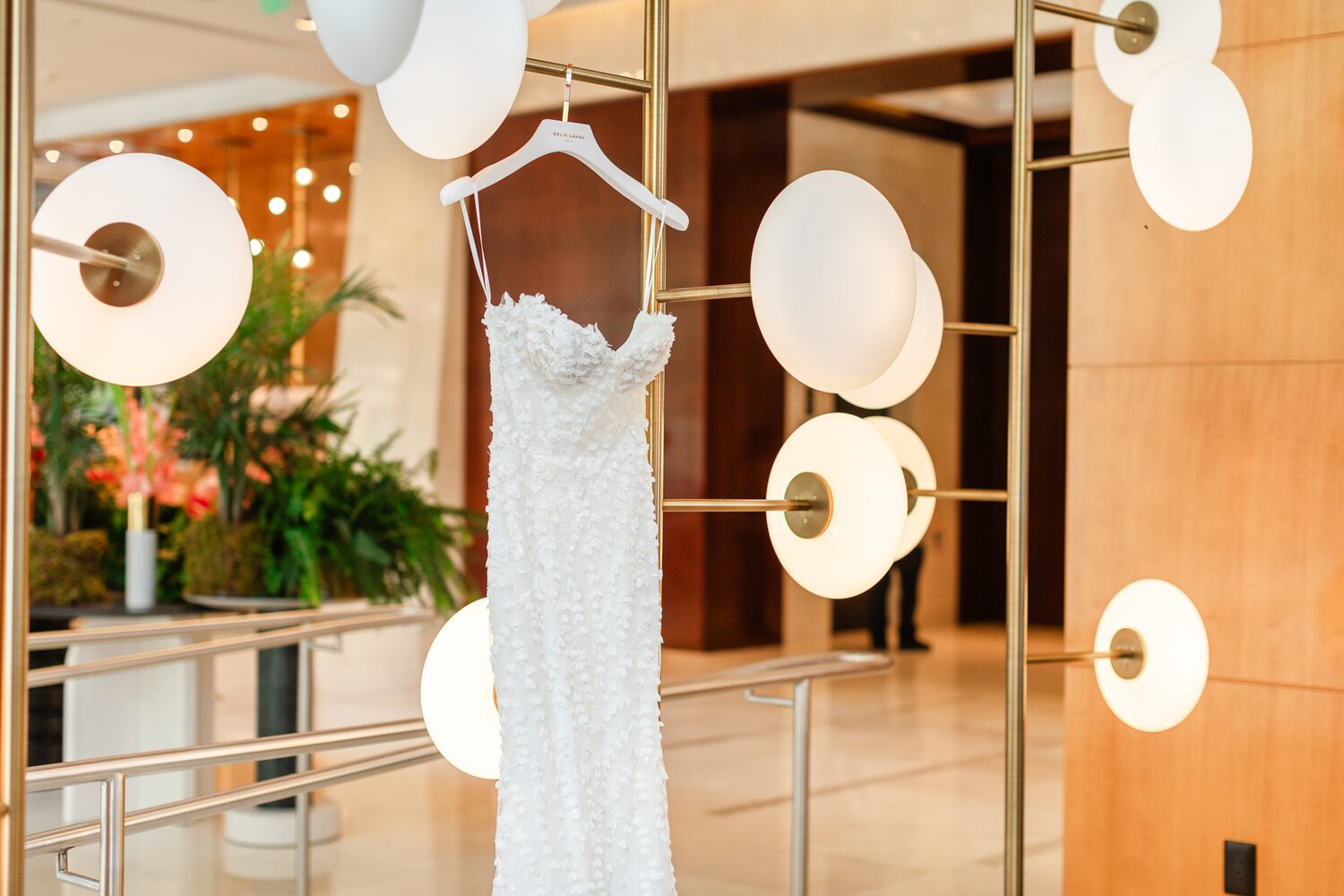 The wedding dress hanging in the light of the lobby before a Mile High Station wedding