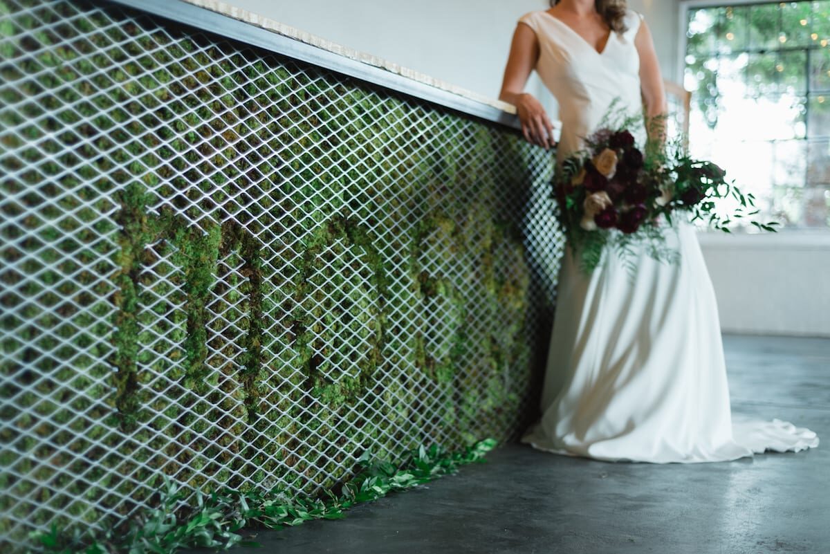 Bride beside the signature moss wall at Moss Denver