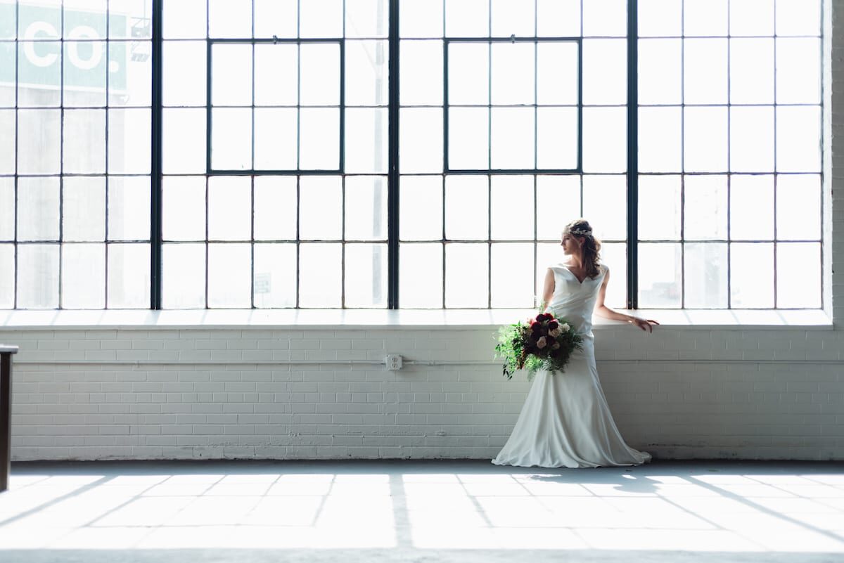 Bride in the light of the tall steel-framed windows at Moss Denver