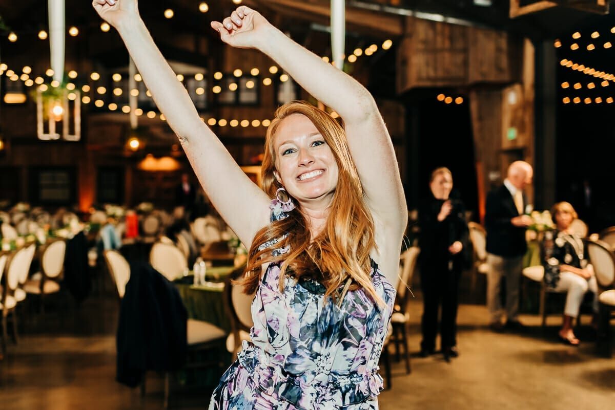 A guest celebrating on the dance floor of the barn at Spruce Mountain Ranch, string lights overhead