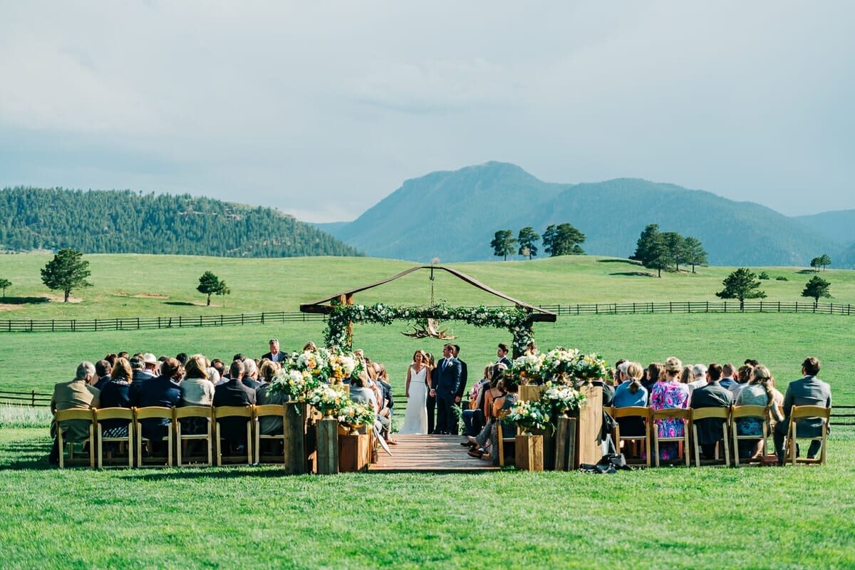 Outdoor wedding ceremony in the meadow with the mountain ridge behind at Spruce Mountain Ranch