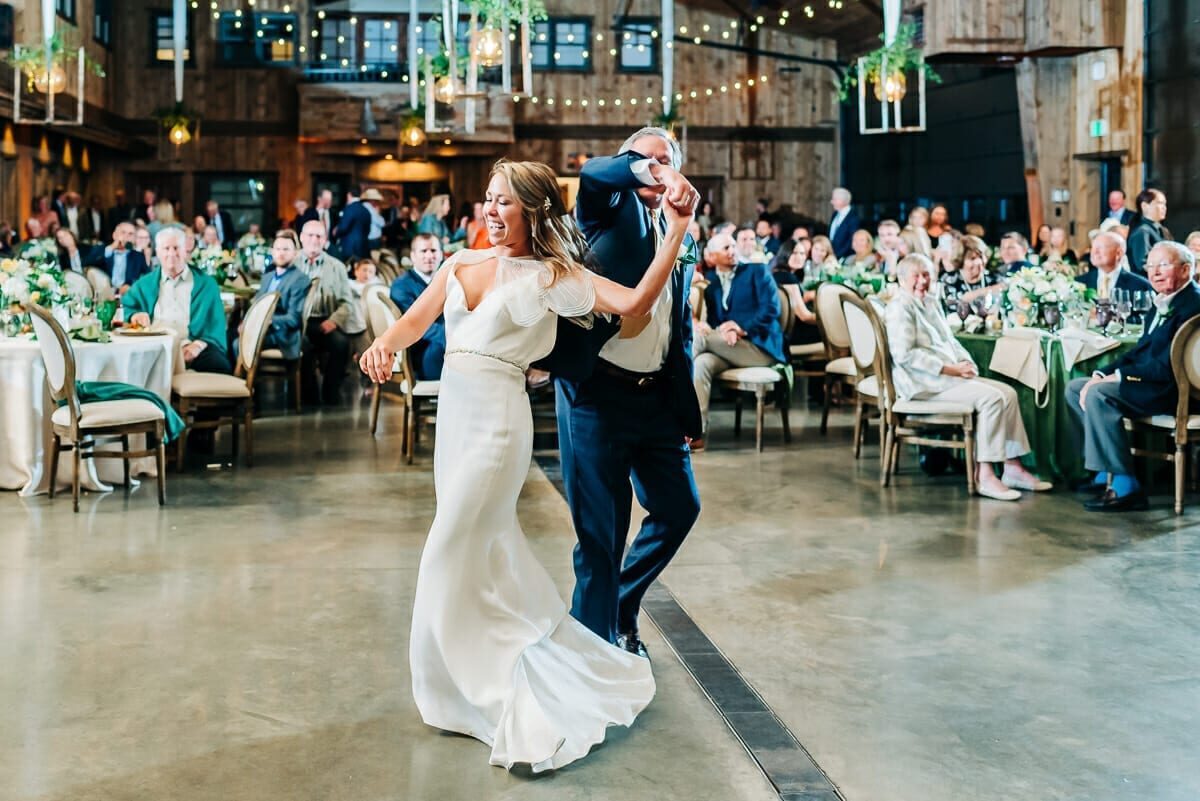 The couple's first dance in the barn at Spruce Mountain Ranch, guests seated around the floor