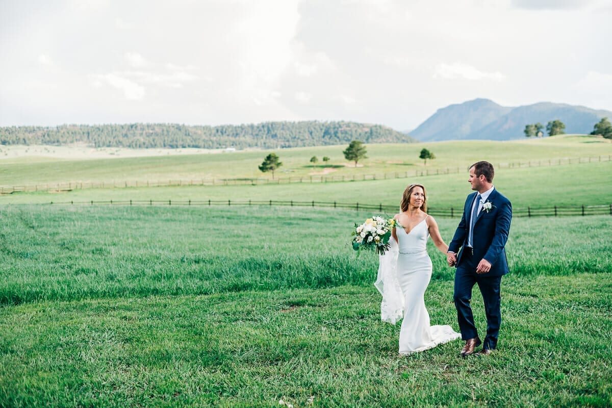 Bride and groom in the open meadow at Spruce Mountain Ranch with the Front Range behind them