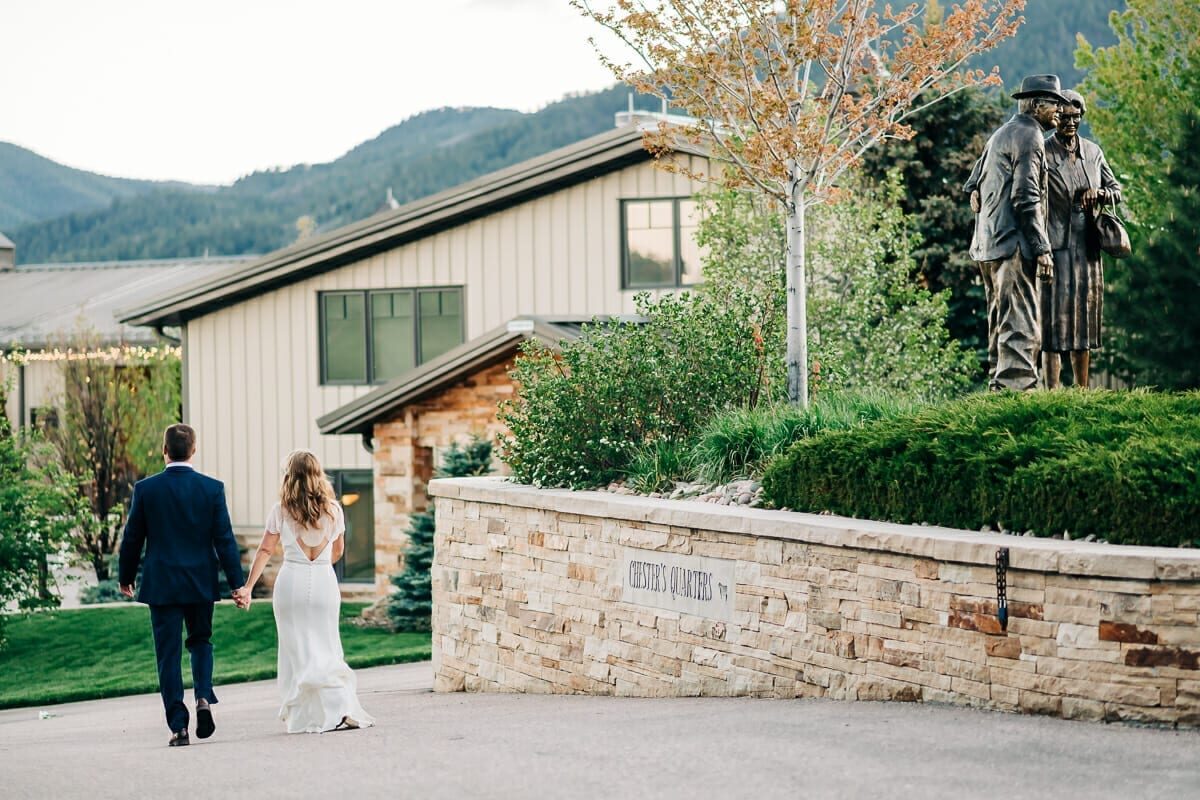 Bride and groom walking toward the lodge buildings at Spruce Mountain Ranch