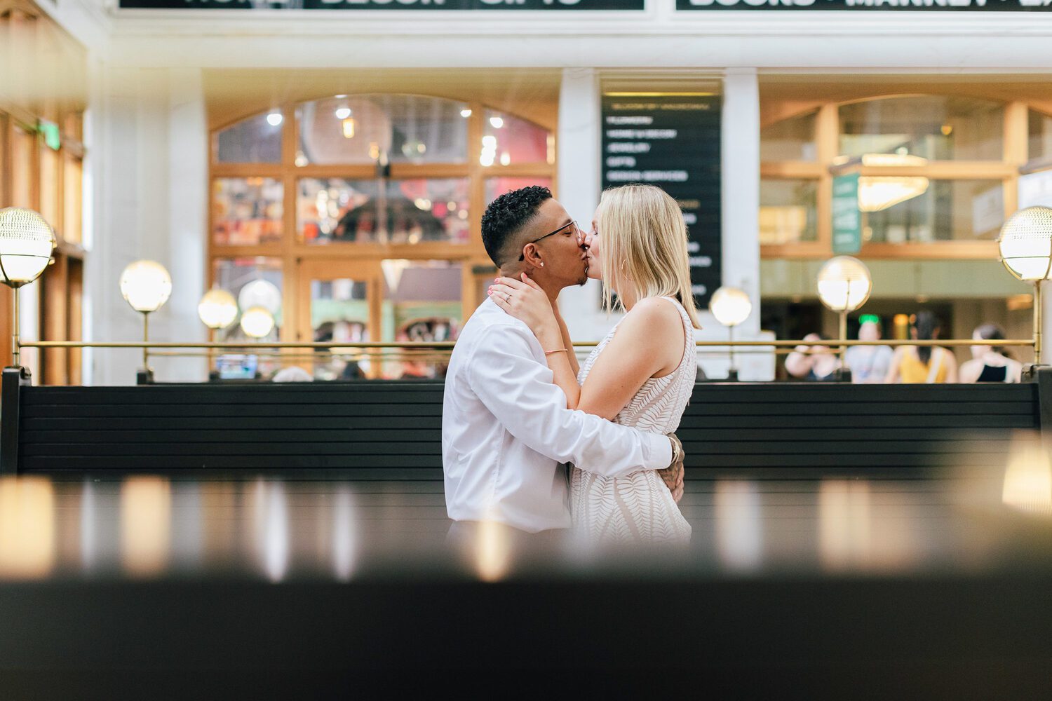 Couple in the Great Hall at Denver Union Station, arched windows and globe lights behind them
