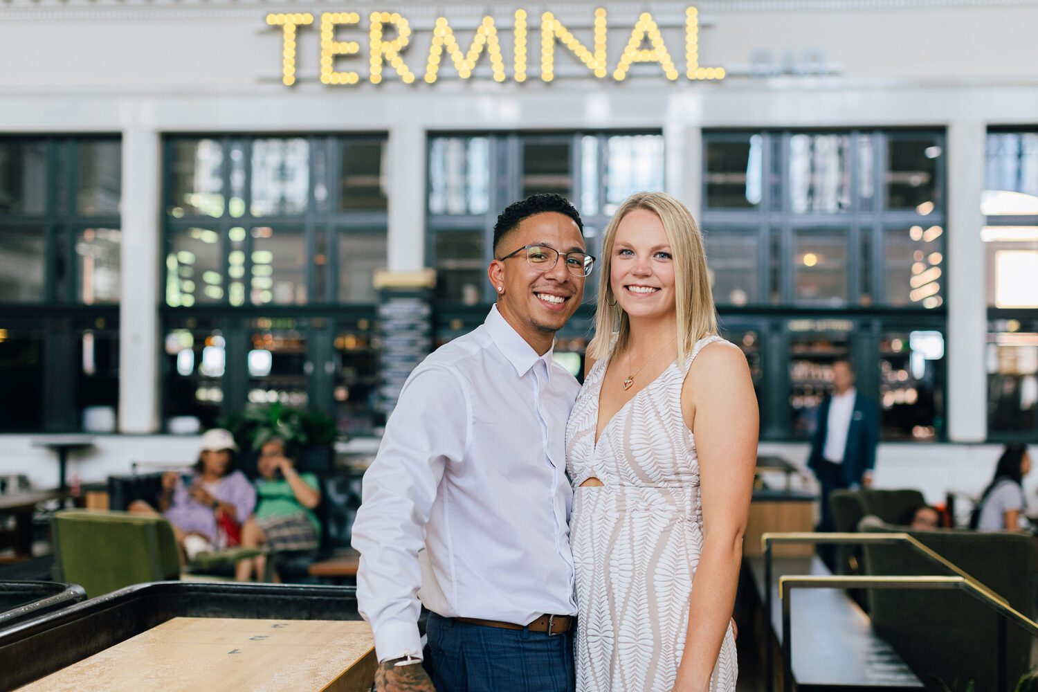 Couple beneath the TERMINAL sign in the Great Hall at Denver Union Station
