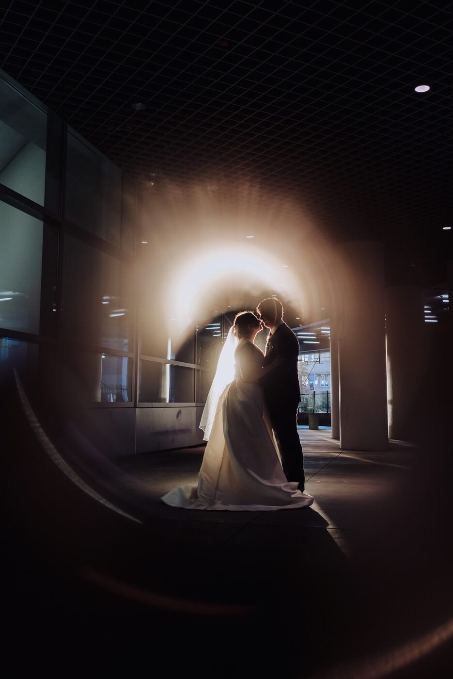 Bride and groom silhouetted in a lit archway at the Denver Athletic Club